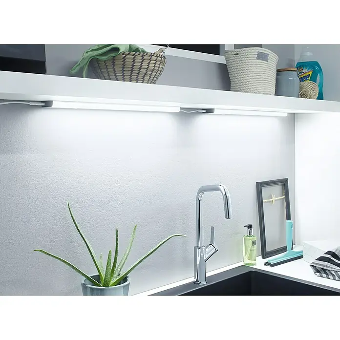 Osram Linear LED-Unterbauleuchte LED Flat - 6 W, Länge: 370 mm, Warmweiß - Nahaufnahme einer Küchenspüle mit Armatur, einer Aloe Vera Pflanze und zwei LED-Unterbauleuchten, die die Arbeitsfläche beleuchten.