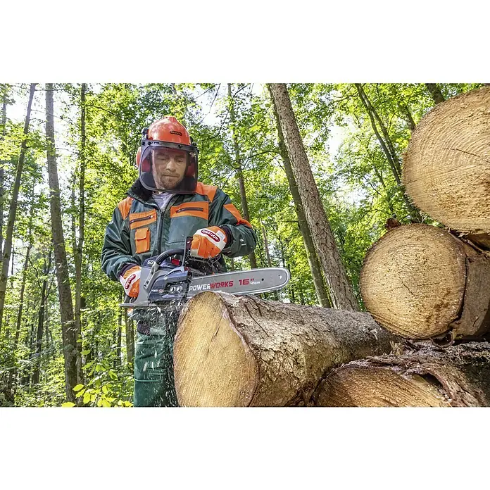 Forst-Schutzhelm - Farbe: Orange, Gehörschutz - Ein Holzarbeiter mit Schutzausrüstung schneidet mit einer Powerworks-Kettensäge Holz. Die Kettensäge POWERWORKS 16" ist scharf und leistungsstark.