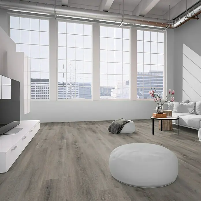 Vinylboden Strong SPC - Bödmeren, Landhausdiele, 1.524 x 228 x 6,5 mm - Ein helles, modernes Wohnzimmer mit großen Fenstern, einem grauen Boden und weißen Möbeln, einschließlich eines großen weißen Sitzsackes im Vordergrund.