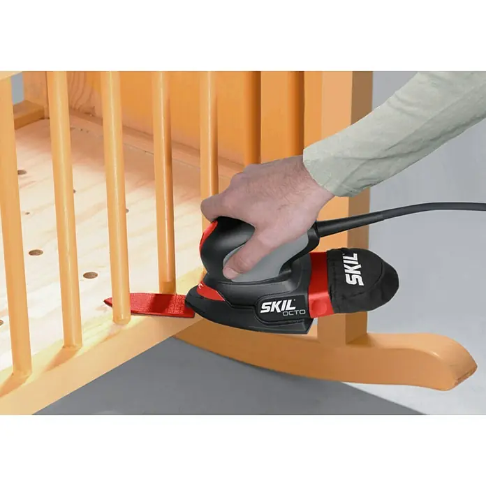 Skil Elektro-Multischleifer 7207 AA - 100 W, Leerlaufschwingzahl: 24.000 U/min, Durchmesser Schwingkreis: 1,6 mm - Nahaufnahme eines SKIL OCTO-Multischleifers, der ein Holzmöbelstück bearbeitet.