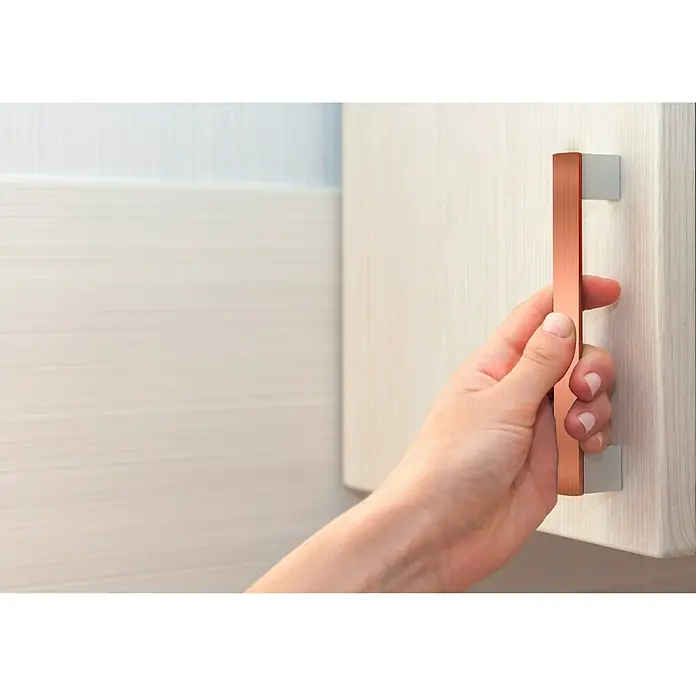 Bellissa Kupferband - Kupfer, Selbstklebend - Nahaufnahme einer Hand, die einen modernen, geradlinigen Möbelgriff aus Kupfer an einer hellen Holzschranktür öffnet.