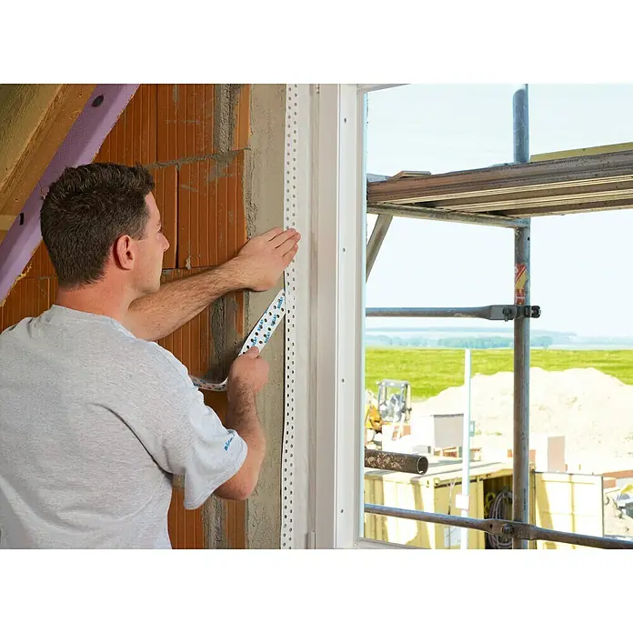 Siga Klebeband Fentrim 20 - 25 m x 100 mm, Innen, Weiß - Ein Mann befestigt Eckschutzprofile an einem Fensterrahmen, um die Kanten zu schützen und eine saubere Oberfläche für die Fertigstellung zu gewährleisten.