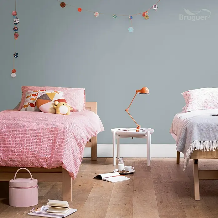 Bruguer Ultra Resist Pintura para paredes - Gris polar, Mate, 4 l - Habitación infantil con dos camas y una lámpara naranja sobre una mesita, decorada con toques de color.