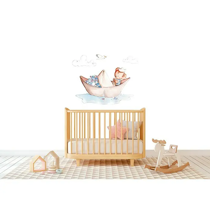 Vinilo de pared Barquito de Papel - Marrón/Azul, Plástico - Habitación infantil con una cuna, un balancín y juguetes, con una pegatina de pared de un niño en un barco de papel.