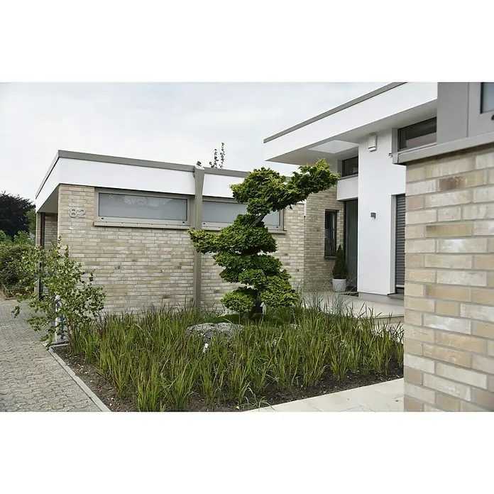 Celina Klinker Verblendstein-Ecke Handstrich Valencia - 21,5 x 6,5 x 10,25 cm, Beige, Steinoptik - Gepflegter Garten mit einem sorgfältig geschnittenen Baum vor einem modernen Haus mit hellen Ziegeln und klaren Linien.