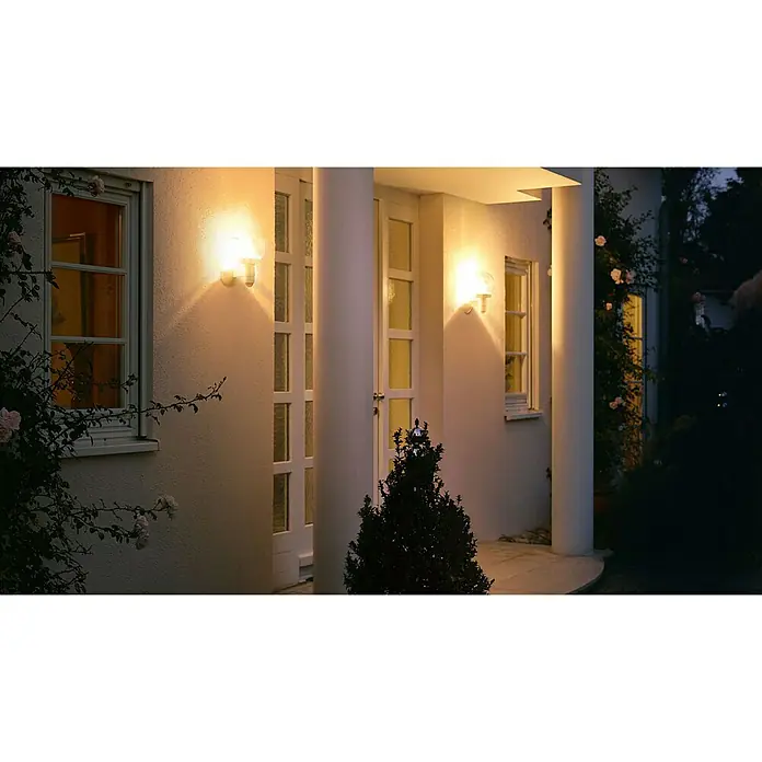 Steinel Aplique exterior con sensor L 115 S - 60 W, L x An x Al: 25,7 x 21,5 x 33 cm - Una fachada de casa con dos luces de pared exteriores iluminadas que emiten una luz cálida y acentúan los detalles arquitectónicos.