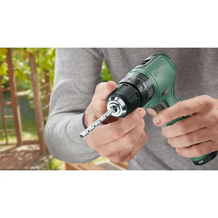 Bosch Taladro atornillador percutor de batería EasyImpact 1200 - 12 V, 1 batería, 1,5 Ah, 30 Nm - Primer plano de un taladro/atornillador inalámbrico verde Bosch con una broca, sostenido por una persona.