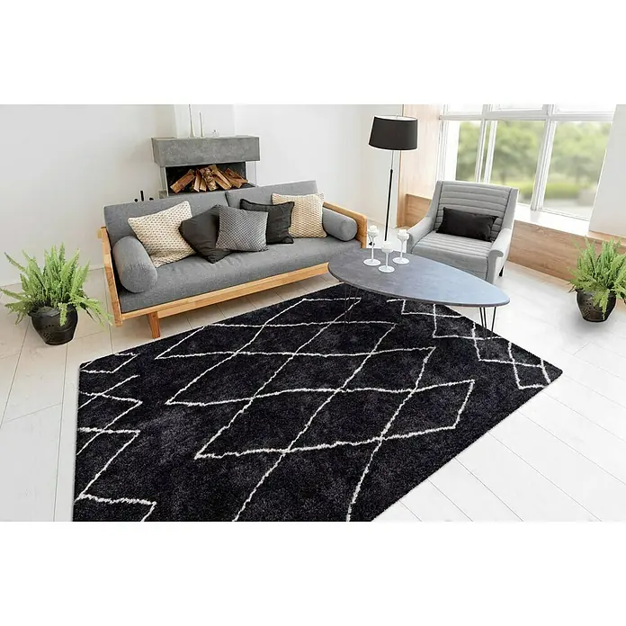 Kayoom Hochflorteppich Orlando 425 - Anthrazit, 230 x 160 cm - Ein stilvoller Raum mit einem schwarzen Teppich mit weißem Rautenmuster, der dem Raum einen modernen Touch verleiht.
