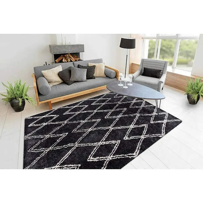 Kayoom Hochflorteppich Orlando 325 - Anthrazit, 150 x 80 cm - Ein modernes Wohnzimmer mit einem schwarzen Teppich mit geometrischen Mustern, der eine gemütliche Atmosphäre schafft.