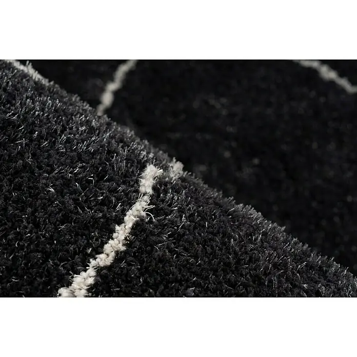 Kayoom Hochflorteppich Orlando 525 - Anthrazit, 230 x 160 cm - Nahaufnahme eines schwarzen Teppichs mit weißen Streifen. Der Teppich hat eine weiche, flauschige Textur und ist ein echter Hingucker.