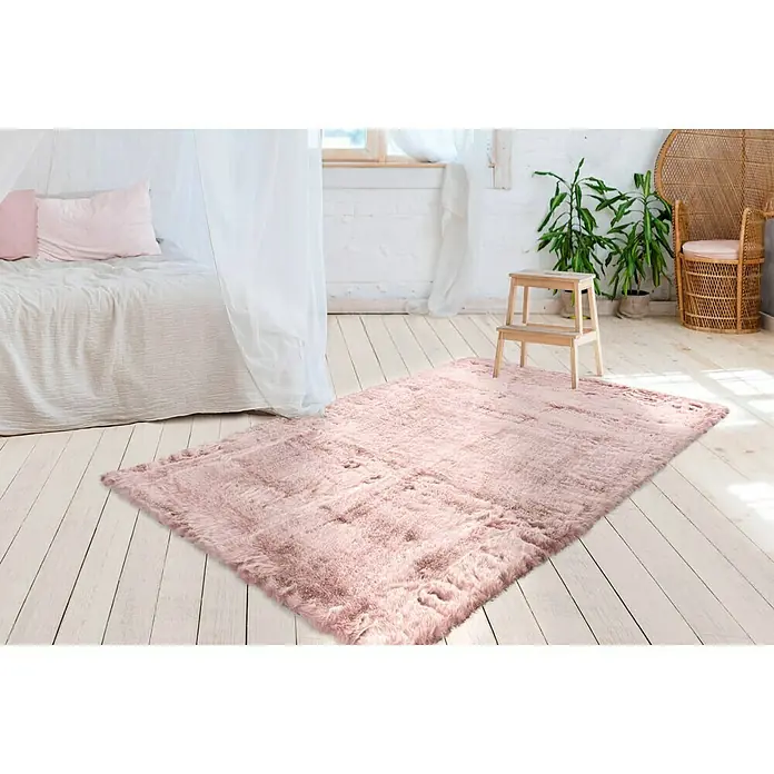 Kayoom Hochflorteppich Tender - Puderrosa, 230 x 160 cm - Ein weicher, rosa Teppich liegt auf einem hellen Holzboden in einem Schlafzimmer und sorgt für Wärme und Komfort.