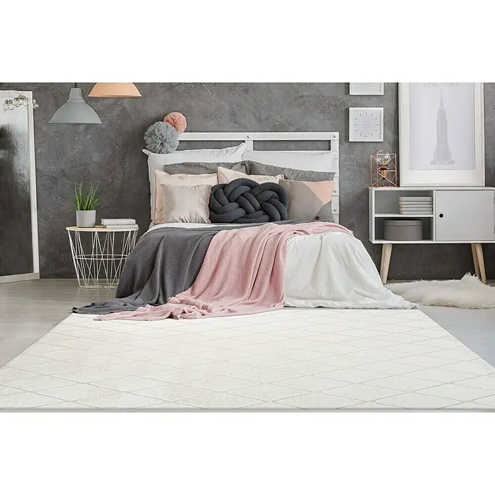 Kayoom Hochflorteppich Vivica 225 - Weiß/Creme, 230 x 160 cm - Ein weißer Teppich mit einem dezenten Rautenmuster liegt in einem stilvollen Schlafzimmer mit modernen Möbeln und sanften Farbtönen.