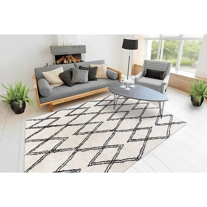 Kayoom Hochflorteppich Orlando 325 - Elfenbein, 290 x 200 cm - Ein Wohnzimmer mit einem cremefarbenen Teppich mit geometrischem Muster, einer grauen Couch und einem grauen Sessel.