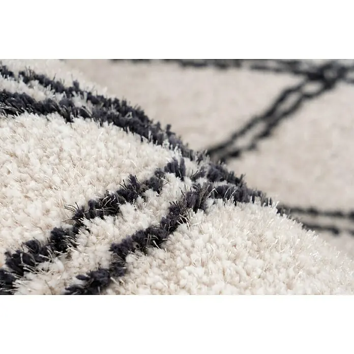 Kayoom Hochflorteppich Orlando 325 - Elfenbein, 290 x 200 cm - Nahaufnahme eines hochflorigen Teppichs mit einem abstrakten schwarzen und weißen Muster, das die weiche Textur hervorhebt.