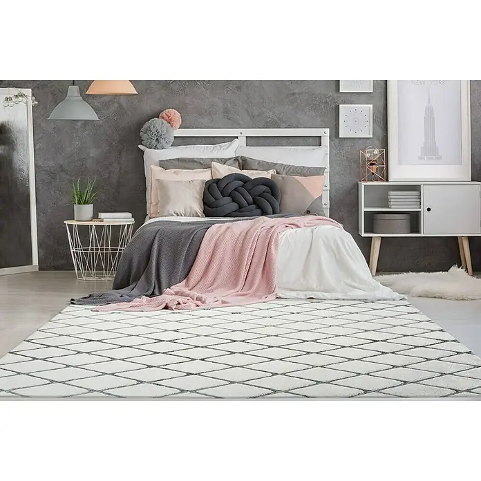 Kayoom Hochflorteppich Vivica 225 - Weiß/Anthrazit, 230 x 160 cm - Ein elegantes Schlafzimmer mit einem stilvollen Teppich mit geometrischem Muster, der dem Raum eine moderne Note verleiht.