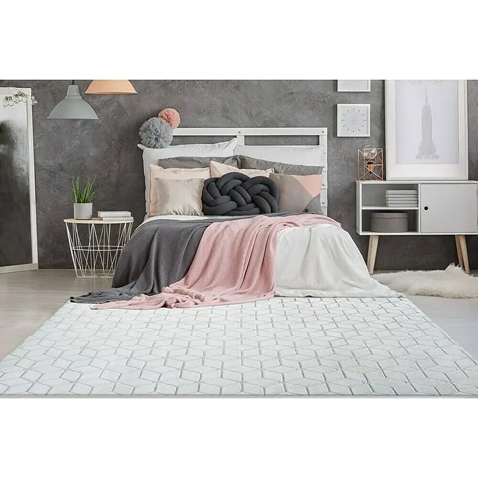 Kayoom Hochflorteppich Vivica 125 - Weiß/Blau, 150 x 80 cm - Ein stilvoller, weißer Teppich mit geometrischem Muster liegt in einem Schlafzimmer und sorgt für eine moderne und einladende Atmosphäre.