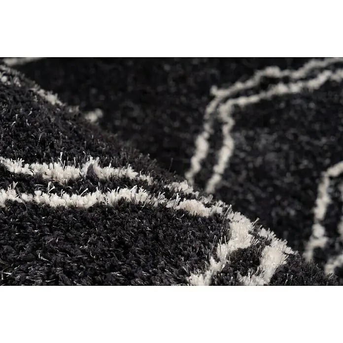 Kayoom Hochflorteppich Orlando 225Anthrazit, 290 x 200 cm, 100 % Polyester - Nahaufnahme eines schwarzen Teppichs mit weißen Akzenten. Der Teppich hat eine weiche, flauschige Textur.