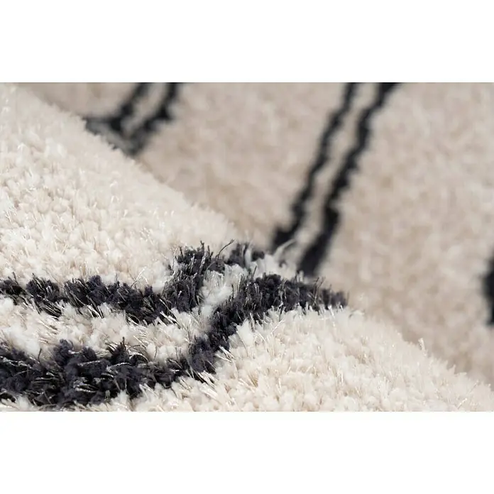 Kayoom Hochflorteppich Orlando 225 - Elfenbein, 290 x 200 cm - Detailaufnahme eines beigen Teppichs mit dunklen geometrischen Mustern, der eine weiche und luxuriöse Textur zeigt.