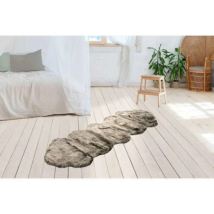 Kayoom Kunstfell Tender doppelt - Grün, 180 x 60 cm - Ein grau-brauner Fellteppich liegt auf einem Holzboden in einem hellen Raum, der dem Interieur eine warme und stilvolle Note verleiht.