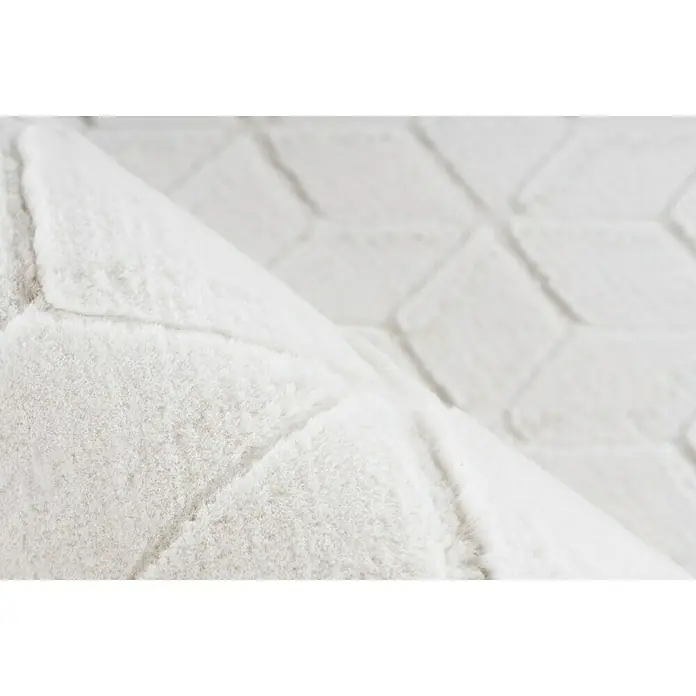 Kayoom Hochflorteppich Vivica 125 - Weiß/Creme, 160 x 120 cm - Detailaufnahme eines weißen Teppichs mit geometrischem Muster, der eine weiche und luxuriöse Textur zeigt.