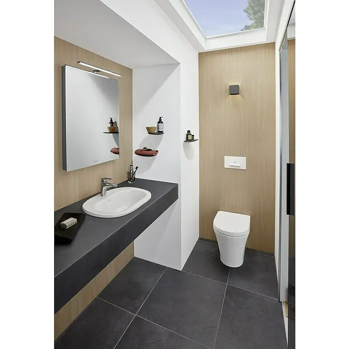 Villeroy & Boch O.novo Einbauwaschbecken - 56 x 40,5 cm, Mit schmutzabweisender Glasur, Hahnloch: Mitte, Ohne Überlauf, Weiß - Ein modernes Badezimmer mit einem schlanken Waschbecken auf einer dunklen Arbeitsplatte und einem beleuchteten Spiegel über einem weißen WC.