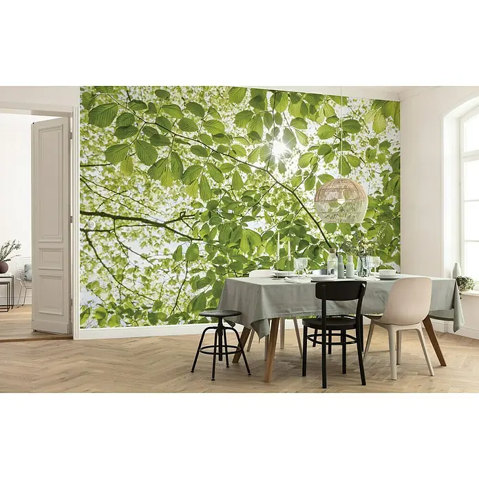 Komar Stefan Hefele Edition 2 Fototapete Im Frühlingswald - 5 -tlg., B x H: 250 x 280 cm, Vlies - Ein Esstisch mit Stühlen und Hocker vor einer Wand mit einem fotorealistischen Blätter-Design, das eine natürliche und entspannende Atmosphäre schafft.