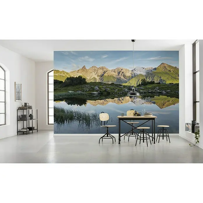 Komar Stefan Hefele Edition 2 Fototapete Allgäu Spiegel - 9 -tlg., B x H: 450 x 280 cm, Vlies - Ein Esstisch mit Hockern steht vor einer Wandtapete mit Bergseeblick, die eine ruhige und einladende Atmosphäre schafft.