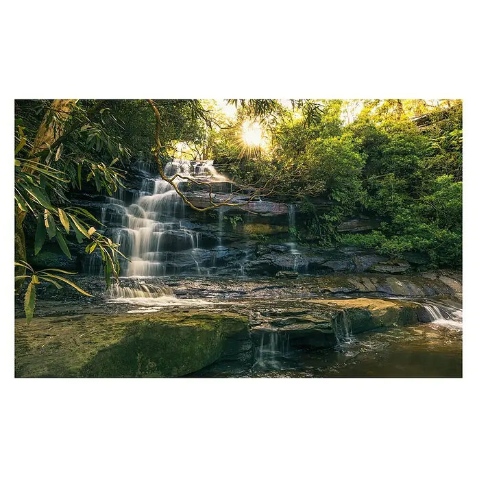 Komar Stefan Hefele Edition 2 Fototapete Golden Falls - 9 -tlg., B x H: 450 x 280 cm, Vlies - Wasserfall im üppigen Grün mit Sonnenstrahlen, die durch das Blätterdach scheinen. Sanfte Kaskaden über Felsen, eine malerische Naturszene.