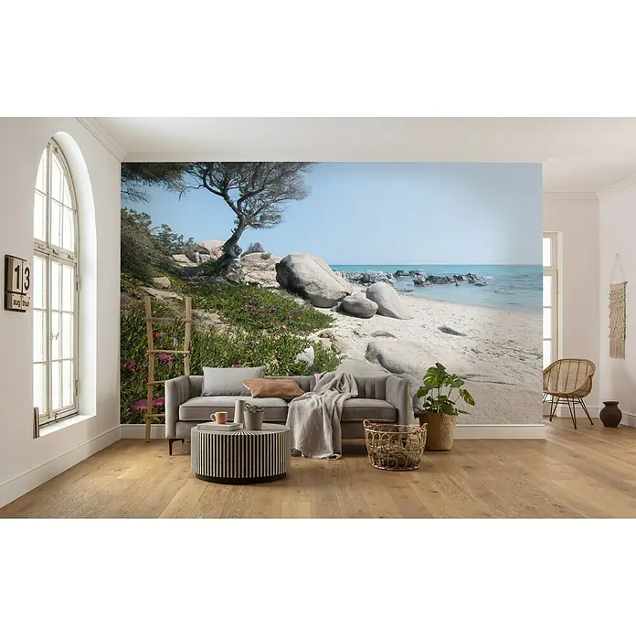 Komar Stefan Hefele Edition 2 Fototapete Mediterrane Träume - 9 -tlg., B x H: 450 x 280 cm, Vlies - Eine stilvolle Inneneinrichtung mit einer Fototapete, die eine ruhige Strandszene zeigt, ergänzt durch ein modernes Sofa und Möbel.