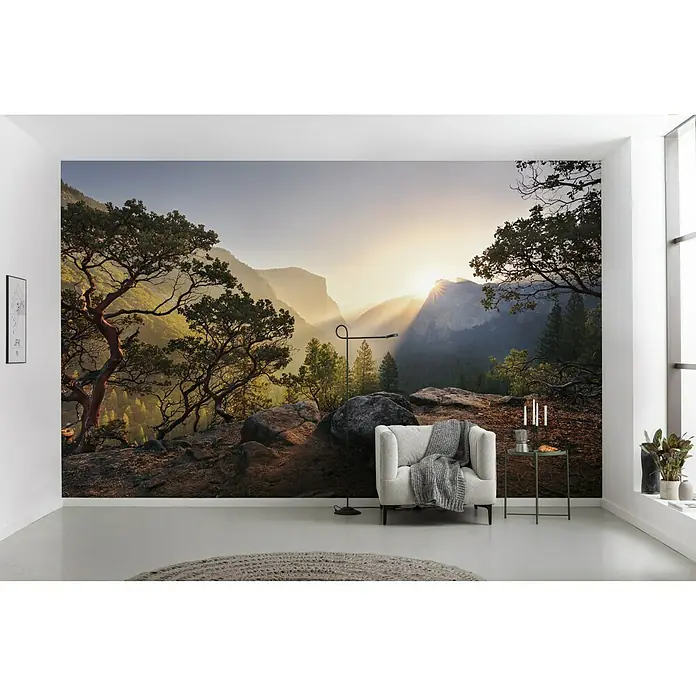 Komar Stefan Hefele Edition 2 Fototapete Yosemites Secret - 9 -tlg., B x H: 450 x 280 cm, Vlies - Ein modernes Interieur mit einem Wandbild, das eine atemberaubende Berglandschaft bei Sonnenaufgang zeigt, ergänzt durch Sessel und Beistelltisch.