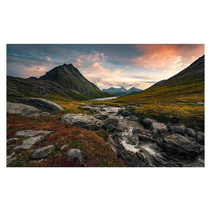 Komar Stefan Hefele Edition 2 Fototapete Schroffes Paradies - 9 -tlg., B x H: 450 x 280 cm, Vlies - Bergbach fließt durch eine alpine Landschaft mit Felsen und Vegetation, im Hintergrund erheben sich majestätische Berge unter einem farbenprächtigen Himmel.