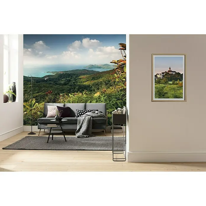 Komar Stefan Hefele Edition 2 Fototapete Heavens Balcony - 9 -tlg., B x H: 450 x 280 cm, Vlies - Wohnzimmer mit einer Couch, einem Teppich und einer Wanddekoration mit tropischem Landschaftsmotiv. Das Poster an der Wand zeigt ein Schloss.