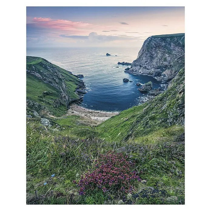 Komar Stefan Hefele Edition 1 Fototapete The Bluebay - 2 -tlg., B x H: 200 x 250 cm, Vlies - Blick auf die Küste mit grünen Hügeln, blauem Wasser und rosa Himmel bei Sonnenuntergang.