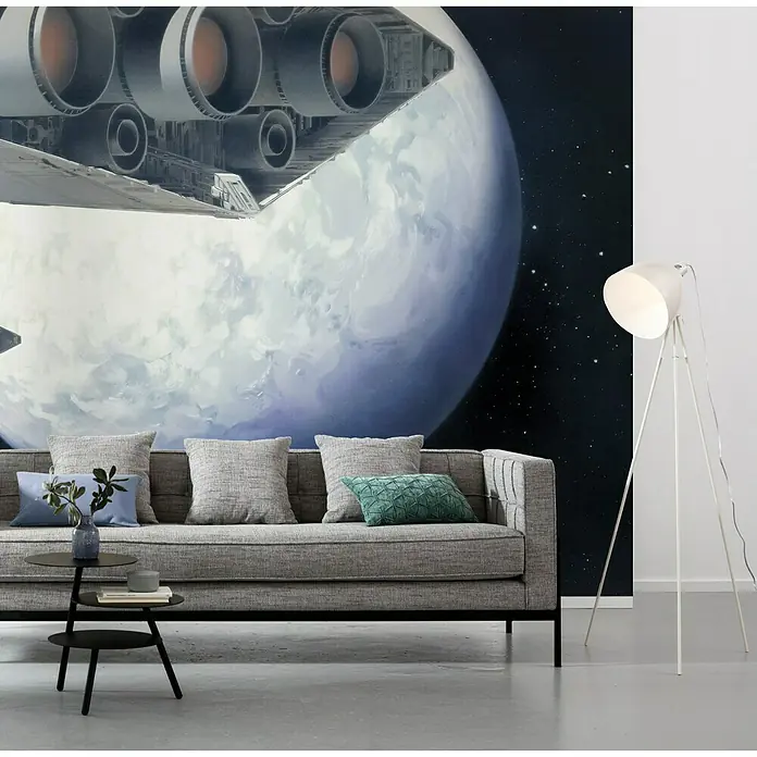 Komar Star Wars Fototapete RMQ Stardestroyer - 10 -tlg., B x H: 500 x 250 cm, Vlies - Graues Sofa mit Kissen vor einer Star Wars Wandtapete, dazu ein schwarzer Beistelltisch und eine weiße Stehlampe.
