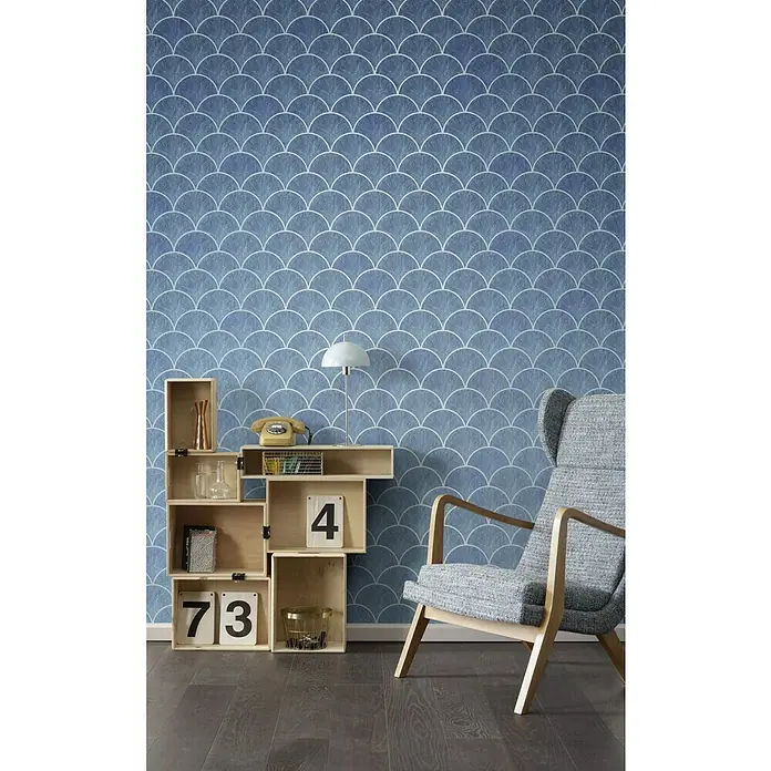 Komar Infinity Fototapete Sea Shanty - 4 -tlg., B x H: 400 x 250 cm, Vlies - Ein elegantes Zimmer mit einer blau gemusterten Tapete, einem Holzregal und einem grauen Sessel, der eine moderne und stilvolle Atmosphäre schafft.