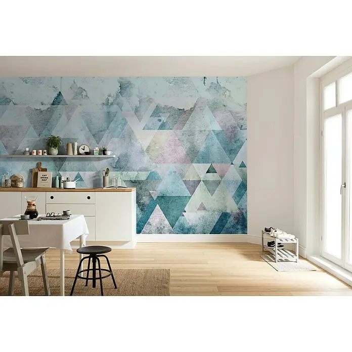 Komar Pure Fototapete Triangles Blue - 4 -tlg., B x H: 400 x 250 cm, Vlies - Ein stilvolles Zimmer mit einer weißen Kommode, einem Esstisch und einer Wand, die mit einem einzigartigen geometrischen Tapetenmuster verziert ist.