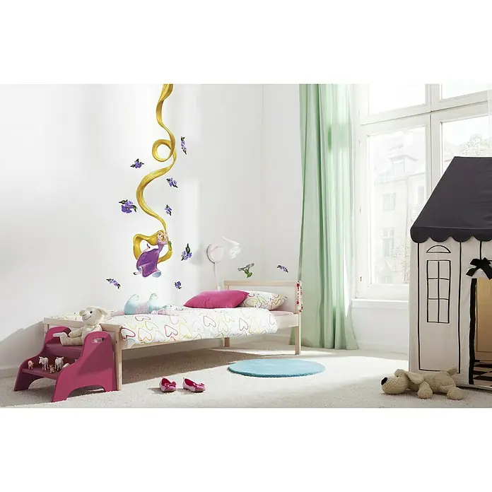 Komar Disney Edition 4 Dekosticker Rapunzel - 15 -tlg., Bunt - Ein helles Kinderzimmer mit einem Bett, das mit Rapunzel-Motiven dekoriert ist, und einem Spielhaus im Hintergrund.