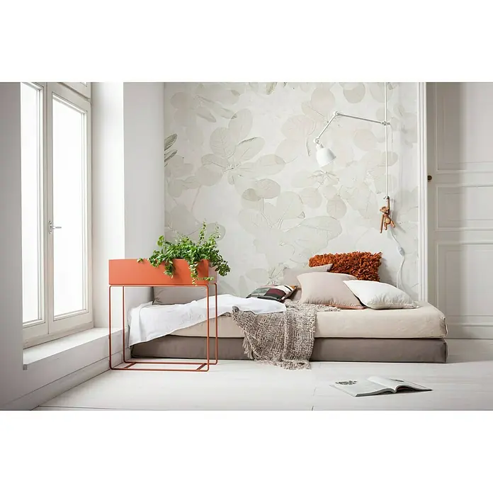 Komar Infinity Fototapete Sheer Grey - 4 -tlg., B x H: 400 x 250 cm, Vlies - Ein Zimmer mit einem trendigen orangefarbenen Pflanzenständer mit einer grünen Pflanze und einem bequemen Bett mit Kissen und einer Decke.