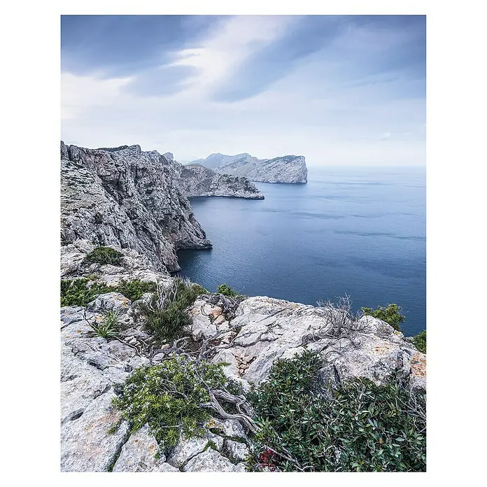 Komar Stefan Hefele Edition 1 Fototapete Bizzare Coast - 2 -tlg., B x H: 200 x 250 cm, Vlies - Küstenlandschaft mit schroffen Klippen und blauem Meer unter bewölktem Himmel. Die Felsen sind mit grüner Vegetation bewachsen.