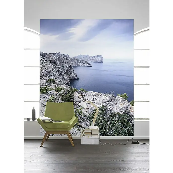 Komar Stefan Hefele Edition 1 Fototapete Bizzare Coast - 2 -tlg., B x H: 200 x 250 cm, Vlies - Das Interieur zeigt eine grüne Sessel, eine Lampe und eine Bücherbox vor einer atemberaubenden Felsküsten-Fototapete für eine ruhige Atmosphäre.