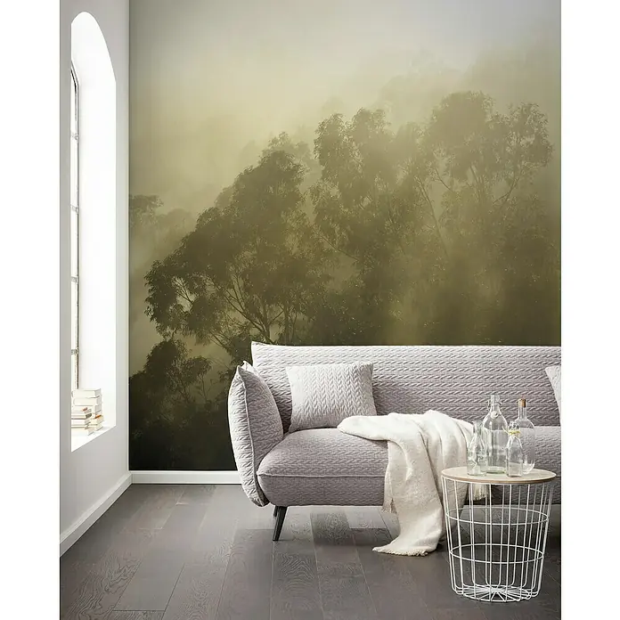Komar Stefan Hefele Edition 1 Fototapete Misty Mountain - 4 -tlg., B x H: 400 x 250 cm, Vlies - Moderner Wohnraum mit einem grauen Sofa, einem Beistelltisch und einer Waldtapete, die eine ruhige Atmosphäre schafft.