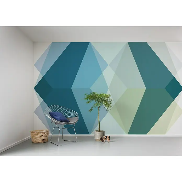 Komar Pure Fototapete Gem Stone Kite - 4 -tlg., B x H: 400 x 250 cm, Vlies - Raum mit einer geometrischen Wandtapete in Blau- und Grüntönen, einem Drahtstuhl und einer Zimmerpflanze, die ein modernes Ambiente schafft.