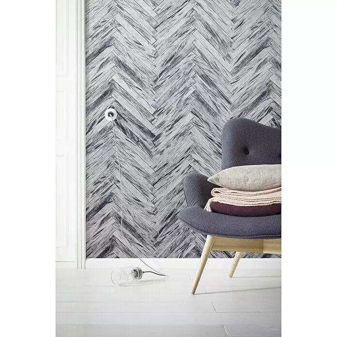 Komar Infinity Fototapete Herringbone Pure - 4 -tlg., B x H: 400 x 250 cm, Vlies - Grau-weiße Tapete im Fischgrätmuster in Holzoptik, im Raum hinter einem grauen Sessel.