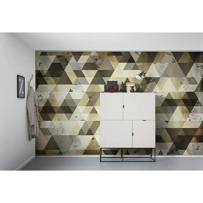Komar Infinity Fototapete Enigma - 4 -tlg., B x H: 400 x 250 cm, Vlies - Bild eines weißen Schranks vor einer Wand mit geometrischem Dreiecksmuster, Bücher und Lampe stehen obenauf.