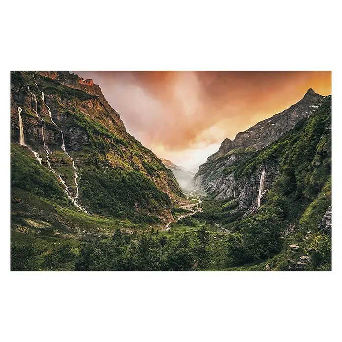 Komar Stefan Hefele Edition 1 Fototapete Eden Valley - 4 -tlg., B x H: 400 x 250 cm, Vlies - Grandiose Berglandschaft mit Wasserfällen, die ins Tal stürzen, unter einem dramatischen, orangefarbenen Himmel. Üppige Vegetation bedeckt die Hänge.