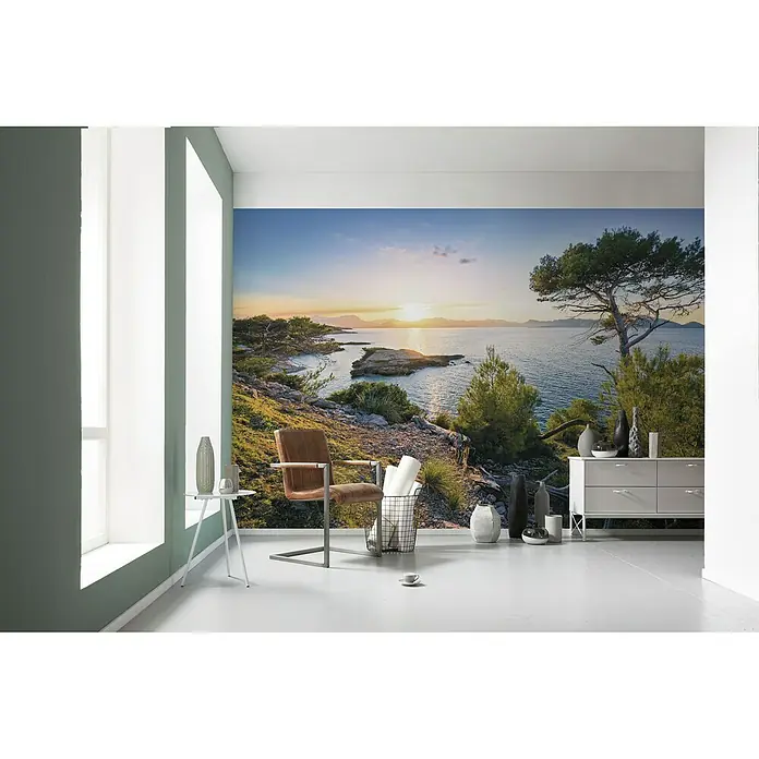 Komar Stefan Hefele Edition 1 Fototapete Southern Light - 4 -tlg., B x H: 400 x 250 cm, Vlies - Ein Raum mit einem Wandbild, das eine malerische Küstenlandschaft zeigt, ergänzt durch moderne Möbel wie einen Stuhl und ein Sideboard.