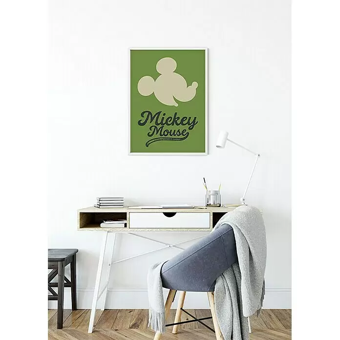 Komar Disney Edition 4 Poster Mickey Mouse Green Head - Disney, B x H: 40 x 50 cm - Ein gerahmtes grünes Poster mit einer hellbeigen Micky-Maus-Silhouette und dem Text 'Mickey Mouse' hängt über einem modernen Schreibtisch.