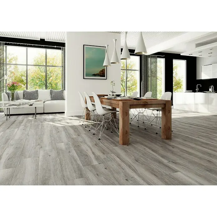 BHS Showroom Pavimento porcelánico Atelier - 120 x 23,3 cm, Gris - Luminoso salón con suelos de madera gris, una mesa de comedor de madera y sillas blancas bajo modernas lámparas colgantes.