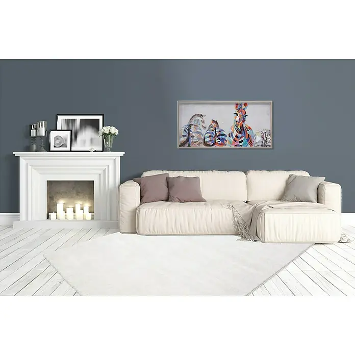 Kurzflorteppich Softtouch - Elfenbein, 150 x 80 cm, 100 % Polypropylen (Flor) - Ein stilvolles Wohnzimmer mit einem weißen Sofa und einem farbenfrohen Zebra-Gemälde, das eine moderne und einladende Atmosphäre schafft.