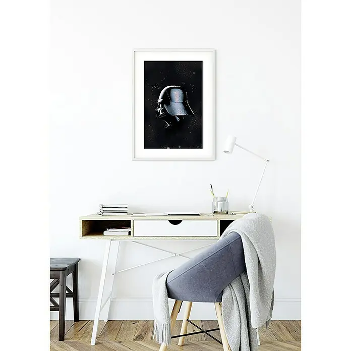 Komar Star Wars Poster Helmets Vader - Star Wars, B x H: 30 x 40 cm - An der Wand hängt ein gerahmtes Bild von Darth Vaders Helm über einem Schreibtisch mit einem Stuhl davor.